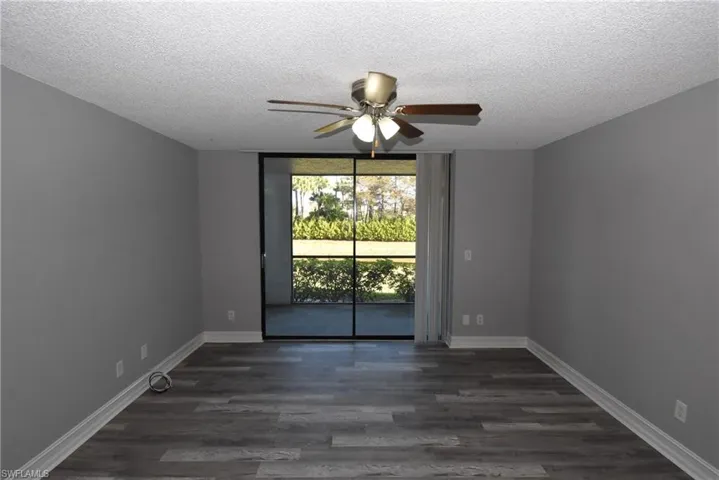 Unfurnished room with dark wood-style floors, expansive windows, ceiling fan, and a textured ceiling