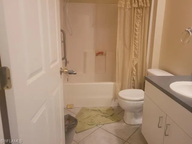 Full bathroom with tile patterned floors, vanity, shower / tub combo, and toilet