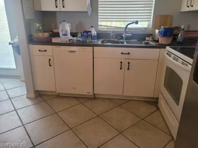 Kitchen with sink, white appliances, and light tile patterned floors
