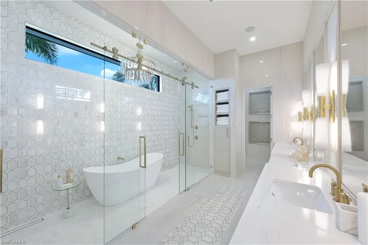 Full bath featuring double vanity, a stall shower, a freestanding tub, and tile walls