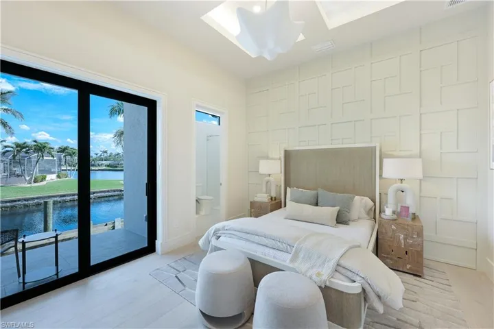 Bedroom featuring an accent wall, a water view, light wood-style floors, and access to outside