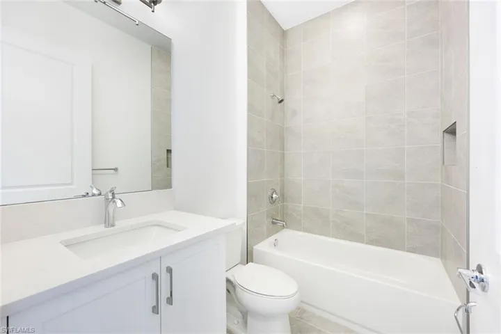 Full bathroom with vanity, toilet, tile patterned floors, and tiled shower / bath
