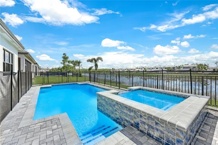 View of pool with an in ground hot tub and a water view