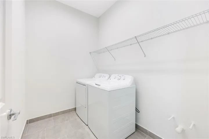 Laundry area with light tile patterned floors and washer and clothes dryer