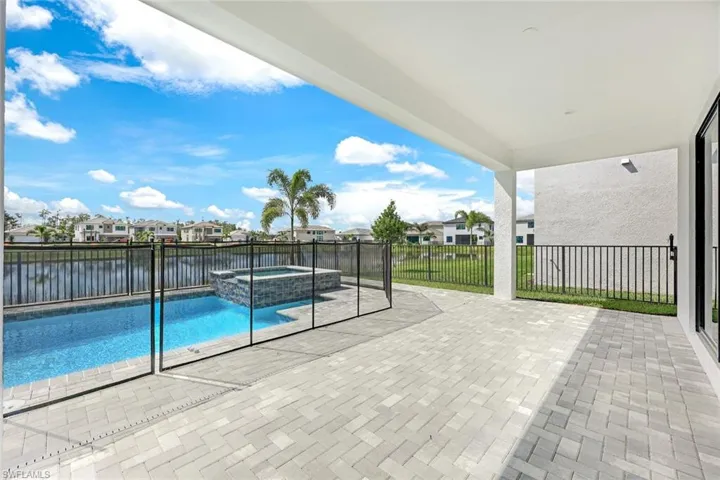 View of swimming pool featuring a water view, a patio, and an in ground hot tub