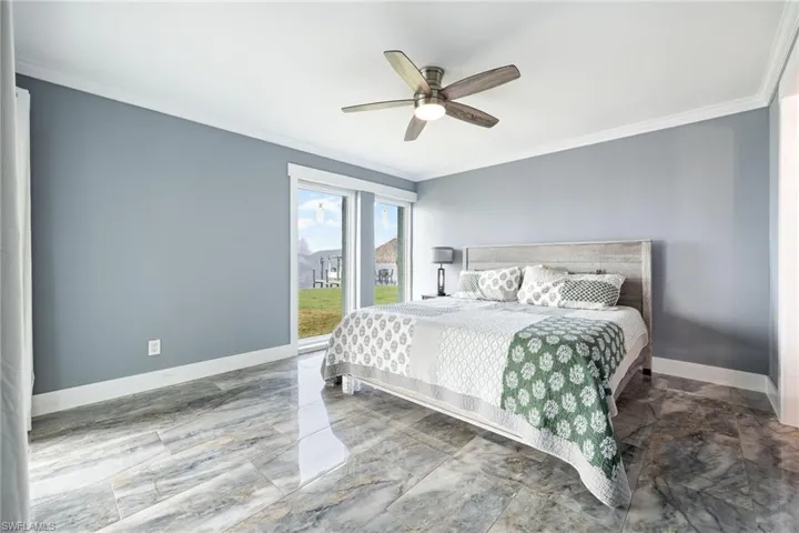 Bedroom with ornamental molding, light marble finish flooring, and a ceiling fan