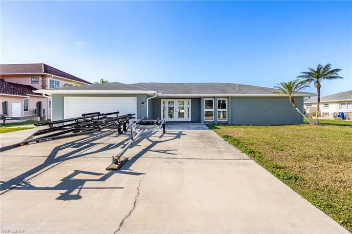View of front of house featuring french doors, an attached garage, driveway, and a front lawn
