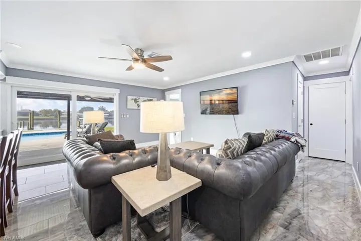 Living area featuring ceiling fan, crown molding, recessed lighting, and marble tiled flooring