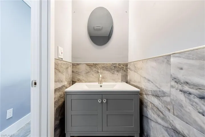 Bathroom featuring vanity, tile walls, and a wainscoted wall