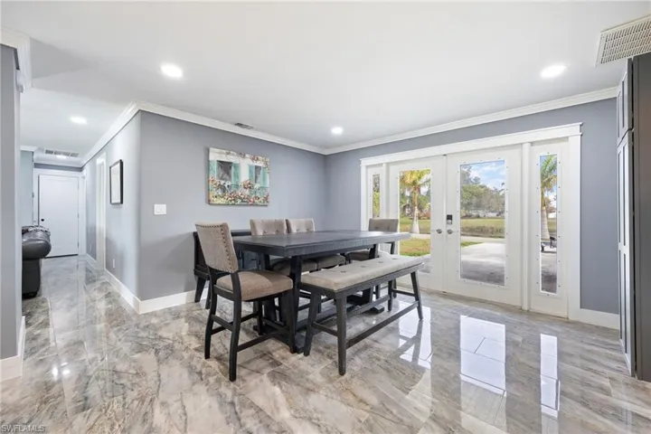 Dining area featuring french doors, ornamental molding, light marble finish floors, and recessed lighting