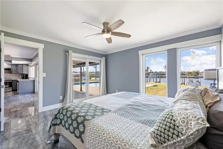 Bedroom featuring access to exterior, marble tiled flooring, ceiling fan, crown molding, and a water view