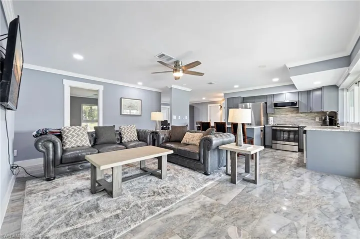 Living room featuring a ceiling fan, crown molding, and recessed lighting