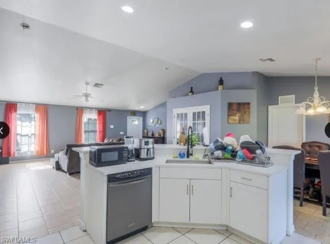 Kitchen island featuring white cabinetry, a stainless steel dishwasher, and a black faucet