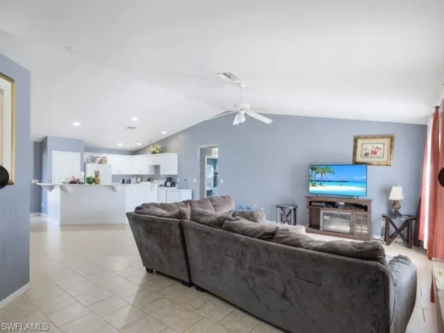 Open-concept living area featuring a vaulted ceiling with a ceiling fan, recessed lighting, and tile flooring