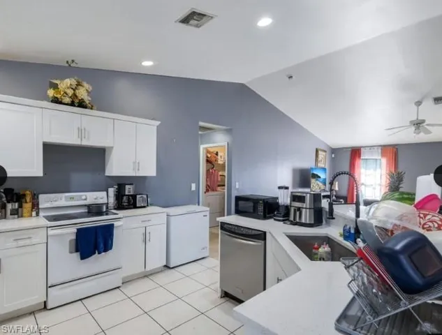 Kitchen featuring white cabinetry, light-toned countertops, tile flooring, stainless steel dishwasher, and a black gooseneck faucet