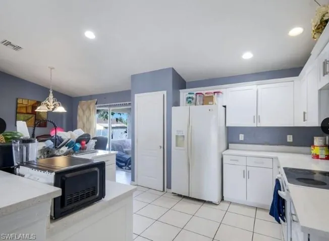 Kitchen featuring white cabinetry, light countertops, white tile flooring, recessed lighting, and a sliding glass door to an outdoor area