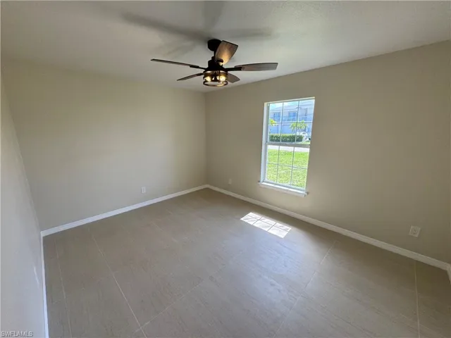 Neutral-toned room with a ceiling fan light fixture, a single window, and light tile flooring