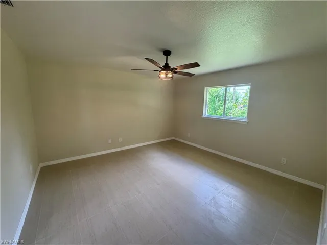 Spacious room featuring large format tile flooring, a contemporary ceiling fan with integrated lighting, and a prominent window