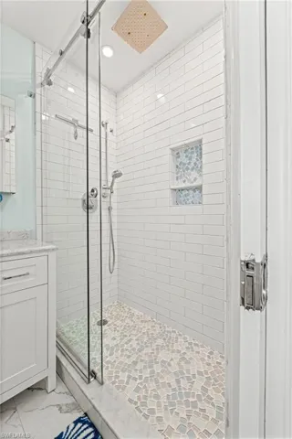 Bathroom with a stall shower, recessed lighting, marble look tiles, and vanity