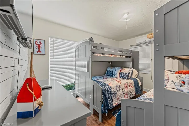 Bedroom with wood finished floors, a textured ceiling, and a wall mounted air conditioner