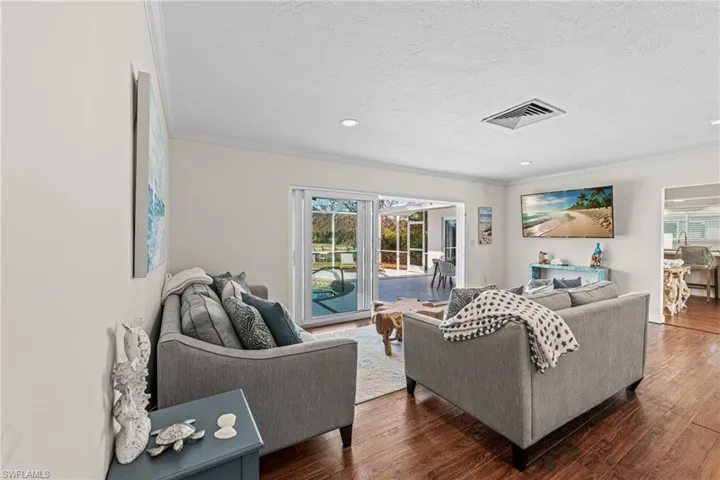 Living area featuring ornamental molding, dark wood-type flooring, a textured ceiling, and recessed lighting