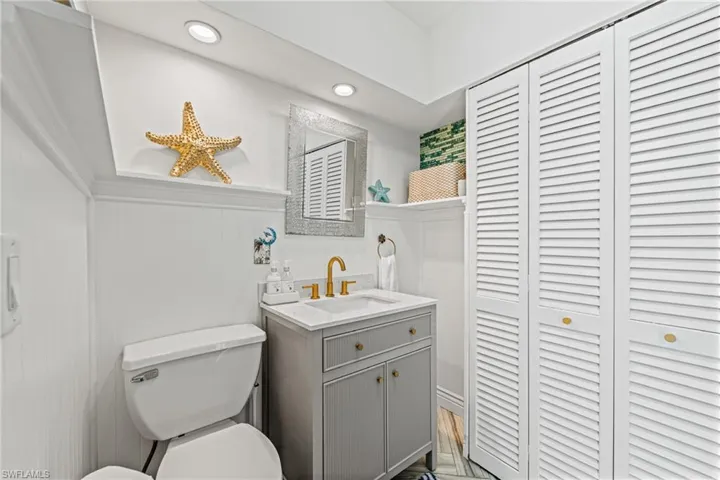Bathroom with a closet, vanity, and recessed lighting