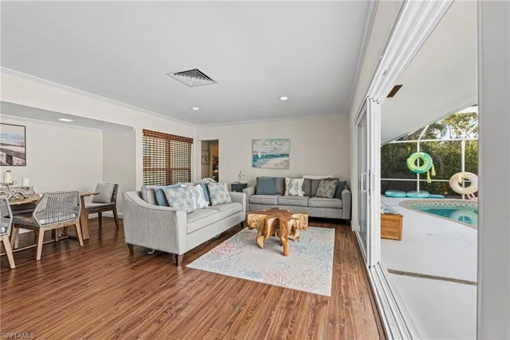 Living area with wood finished floors, crown molding, and recessed lighting