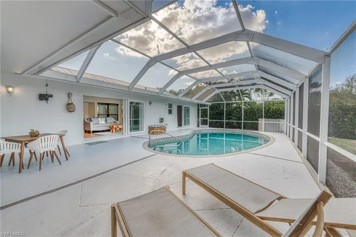 Outdoor pool with a patio area and glass enclosure