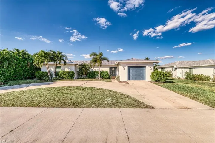 Single story home with driveway, stucco siding, a front yard, and a garage