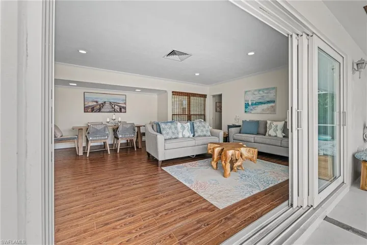 Living area featuring wood finished floors, ornamental molding, and recessed lighting