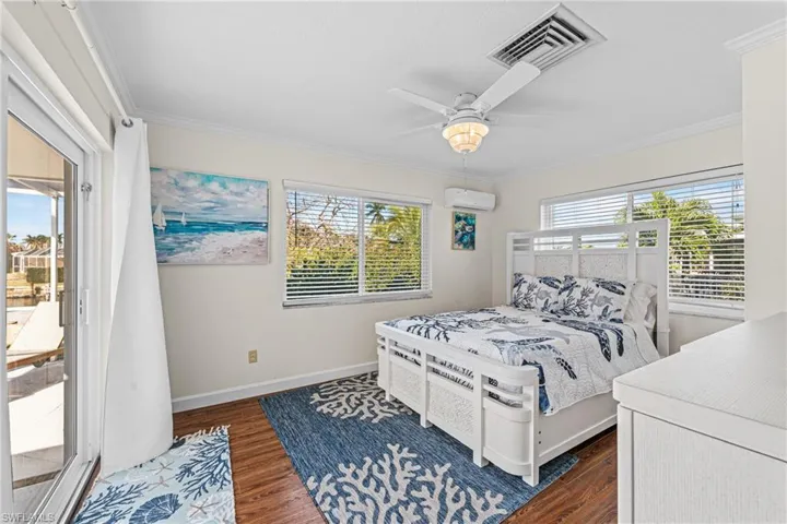 Bedroom featuring ornamental molding, an AC wall unit, access to outside, dark wood finished floors, and a ceiling fan