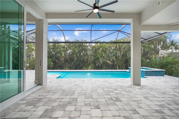 View of swimming pool featuring ceiling fan, a patio area, glass enclosure, and an in ground hot tub
