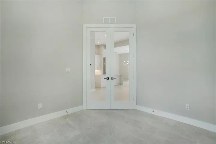 Unfurnished bedroom featuring a chandelier and french doors