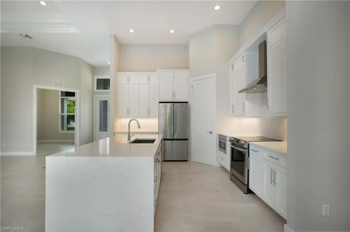 Kitchen featuring white cabinetry, stainless steel appliances, sink, and an island with sink