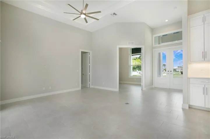 Unfurnished living room featuring ceiling fan, a high ceiling, and light tile patterned flooring
