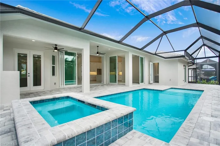 View of pool with french doors, an in ground hot tub, glass enclosure, ceiling fan, and a patio