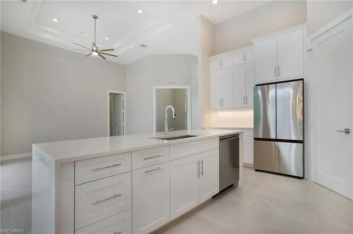 Kitchen featuring white cabinets, appliances with stainless steel finishes, and a raised ceiling