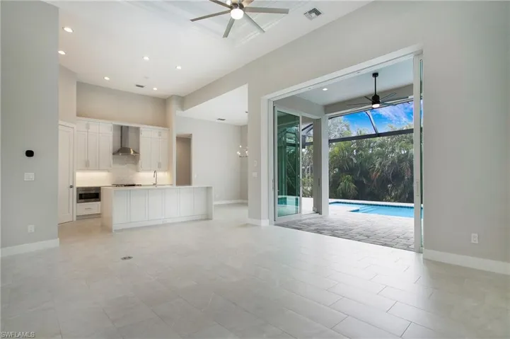 Unfurnished living room with sink, light tile patterned floors, and ceiling fan