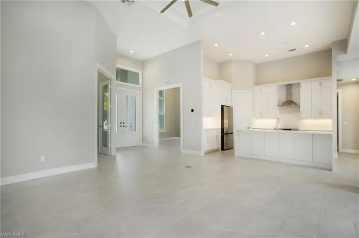 Unfurnished living room featuring sink, light tile patterned floors, ceiling fan, and a towering ceiling