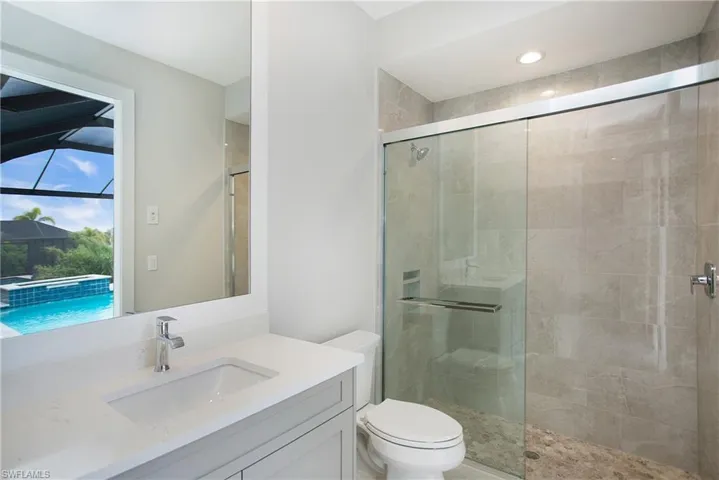 Bathroom featuring walk in shower, vanity, and toilet