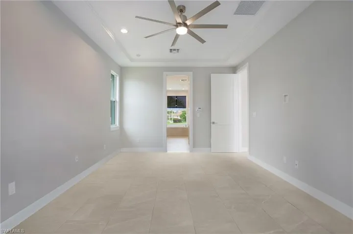 Unfurnished room featuring light tile patterned floors, ceiling fan, and a raised ceiling