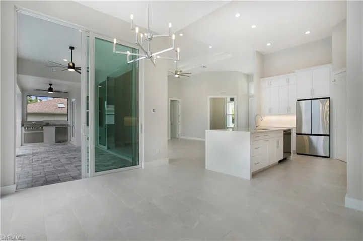 Kitchen with white cabinetry, sink, appliances with stainless steel finishes, hanging light fixtures, and a notable chandelier