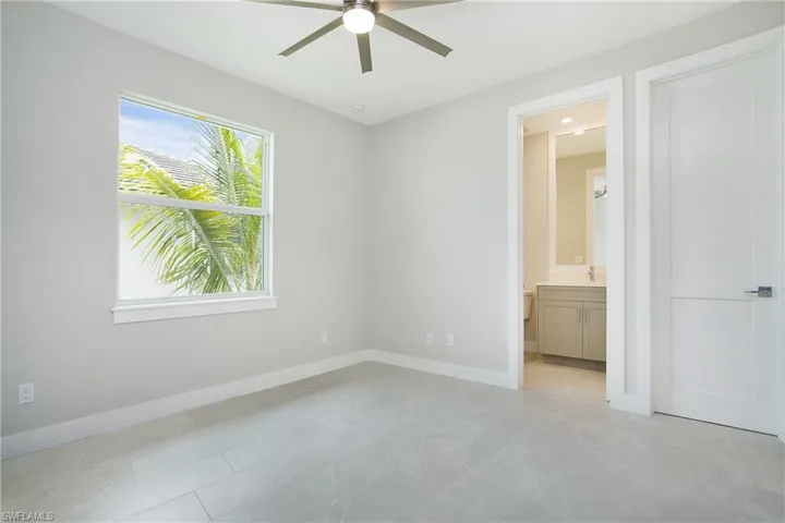 Unfurnished bedroom featuring ceiling fan and ensuite bath