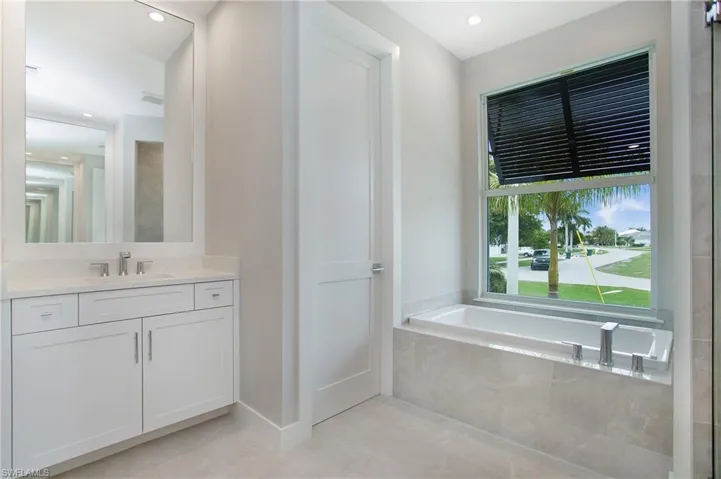 Bathroom featuring vanity, a relaxing tiled tub, and tile patterned flooring