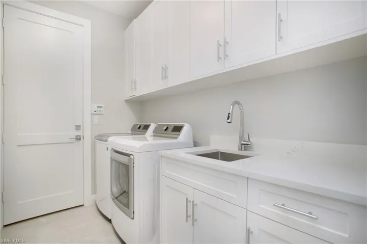 Washroom with cabinets, washer and dryer, and sink