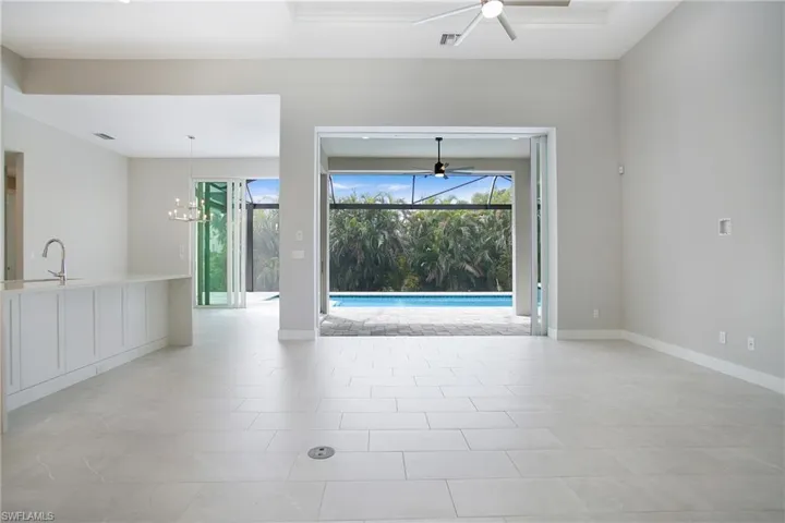 Spare room with light tile patterned floors, a healthy amount of sunlight, and ceiling fan with notable chandelier