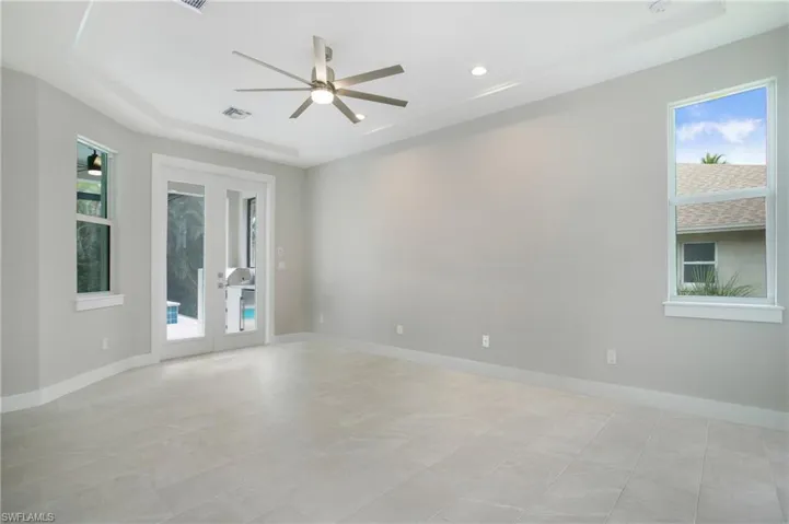Tiled spare room with french doors, ceiling fan, and a raised ceiling