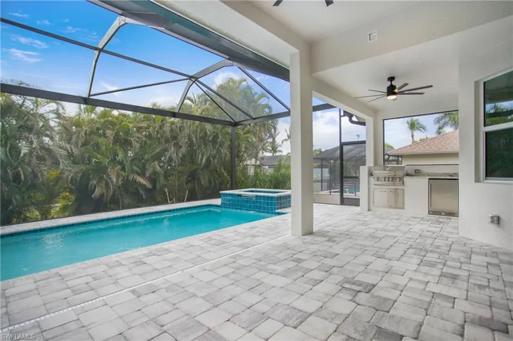 View of pool with a lanai, area for grilling, a patio, and an in ground hot tub