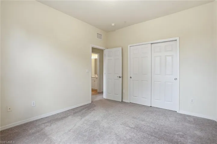 Unfurnished bedroom with light carpet and a closet