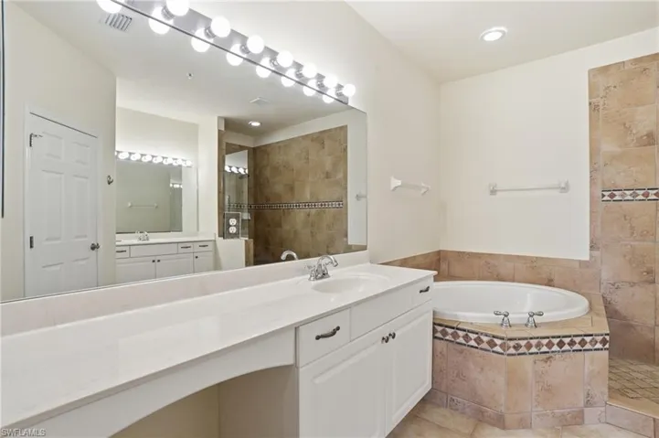 Full bathroom with a walk in shower, vanity, a garden tub, and light tile patterned floors